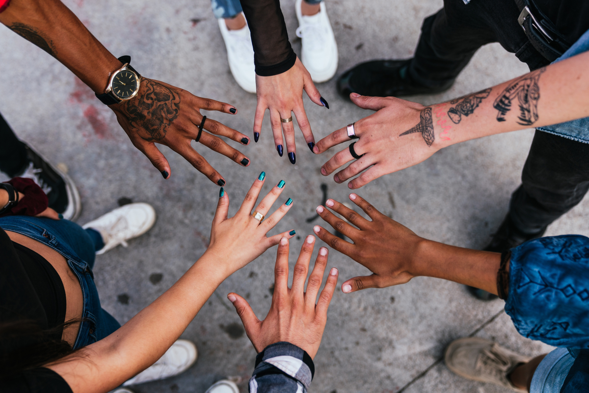 Group of five hands joining together in the center of the photo.